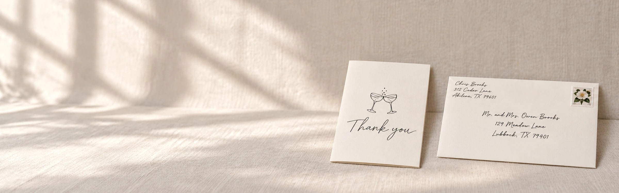 A tall stack of hand-addressed wedding thank-you envelopes with one card open in front